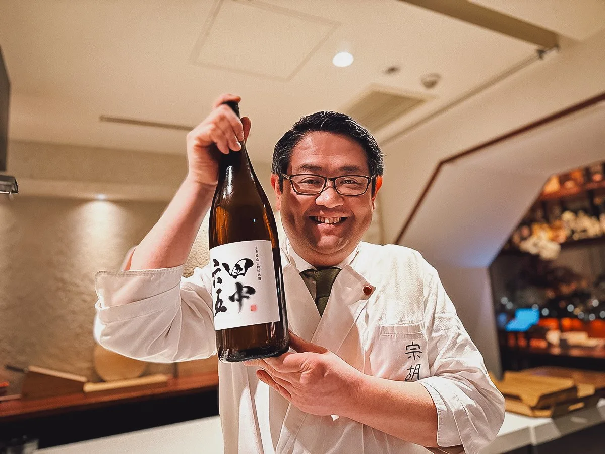 Chef Nomura showing off a bottle of sake